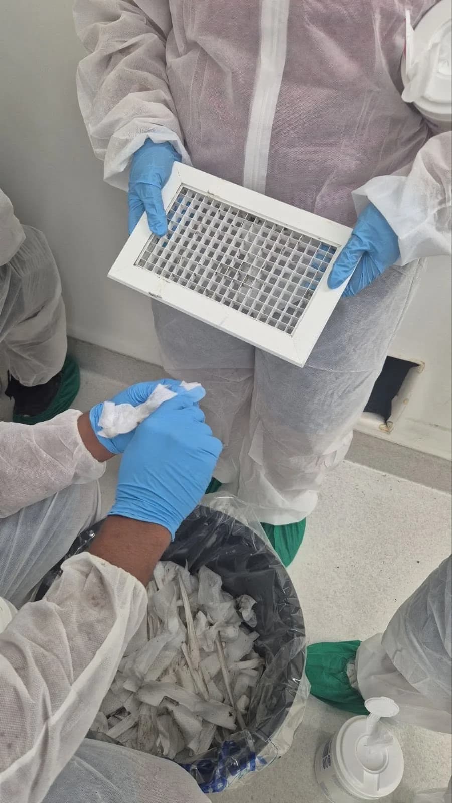Gloved cleaning team members wiping a ventilation grille at CWM