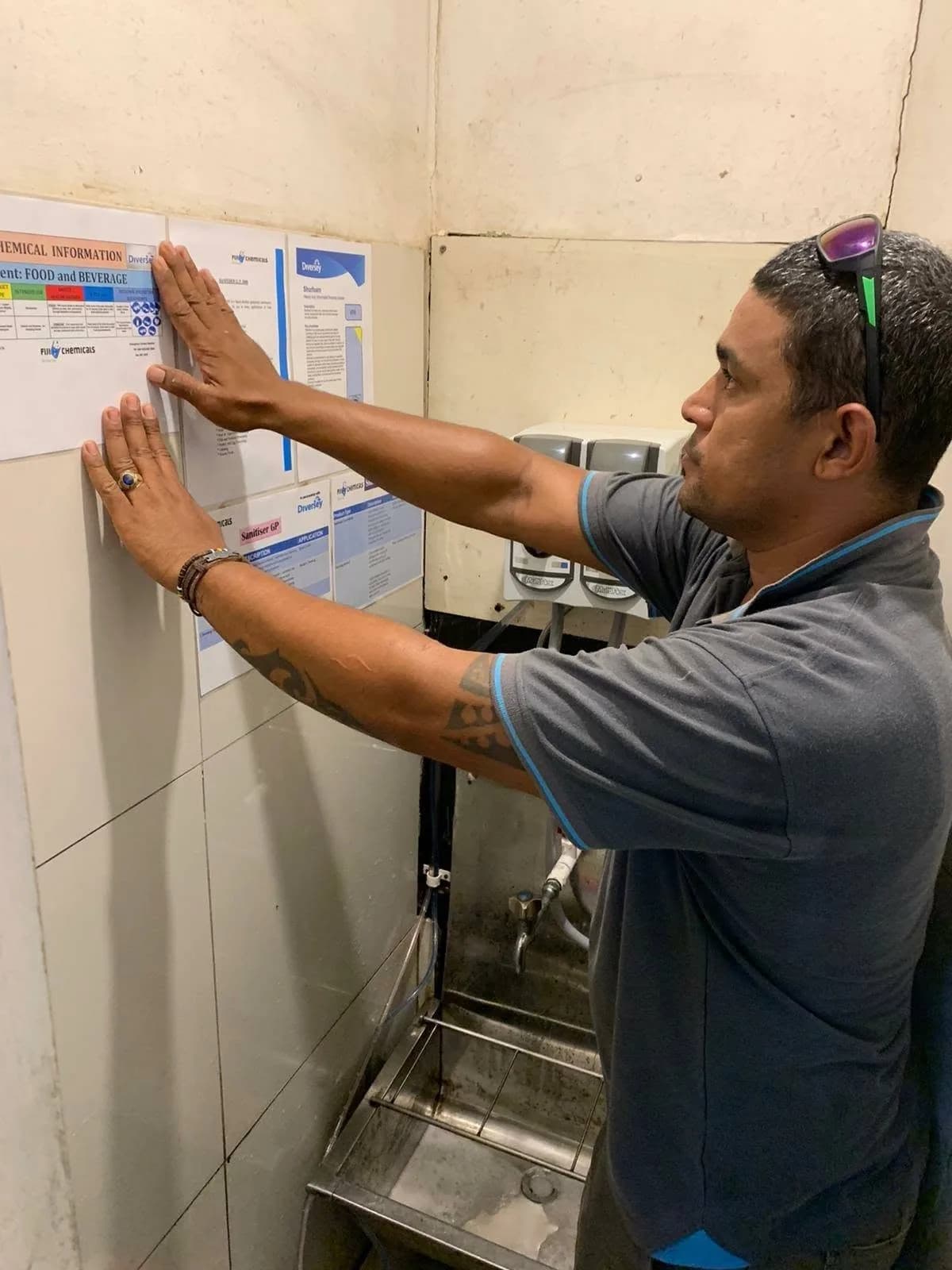FCL team member fitting a chemical information chart beside dosing dispensers
