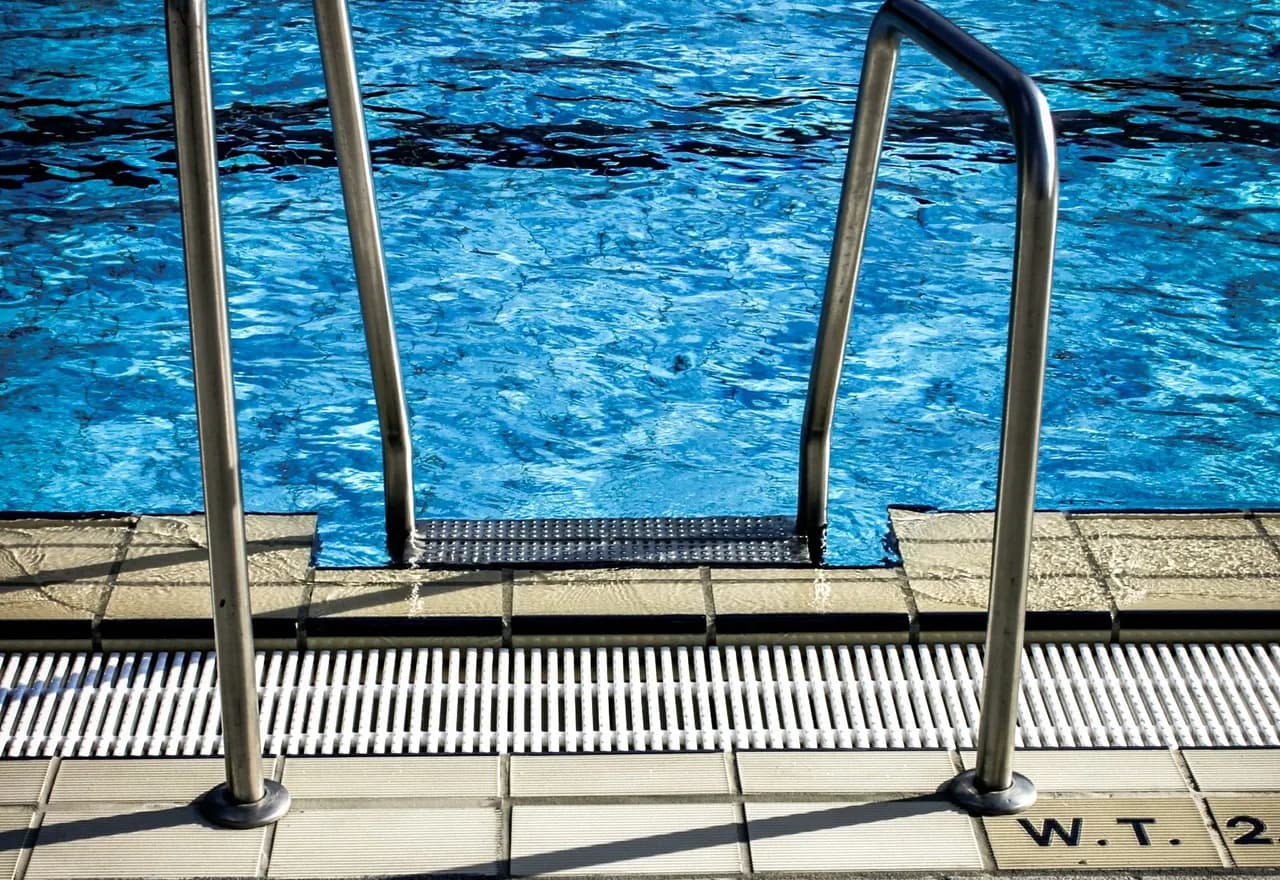 A metal pool ladder beside clear blue swimming pool water