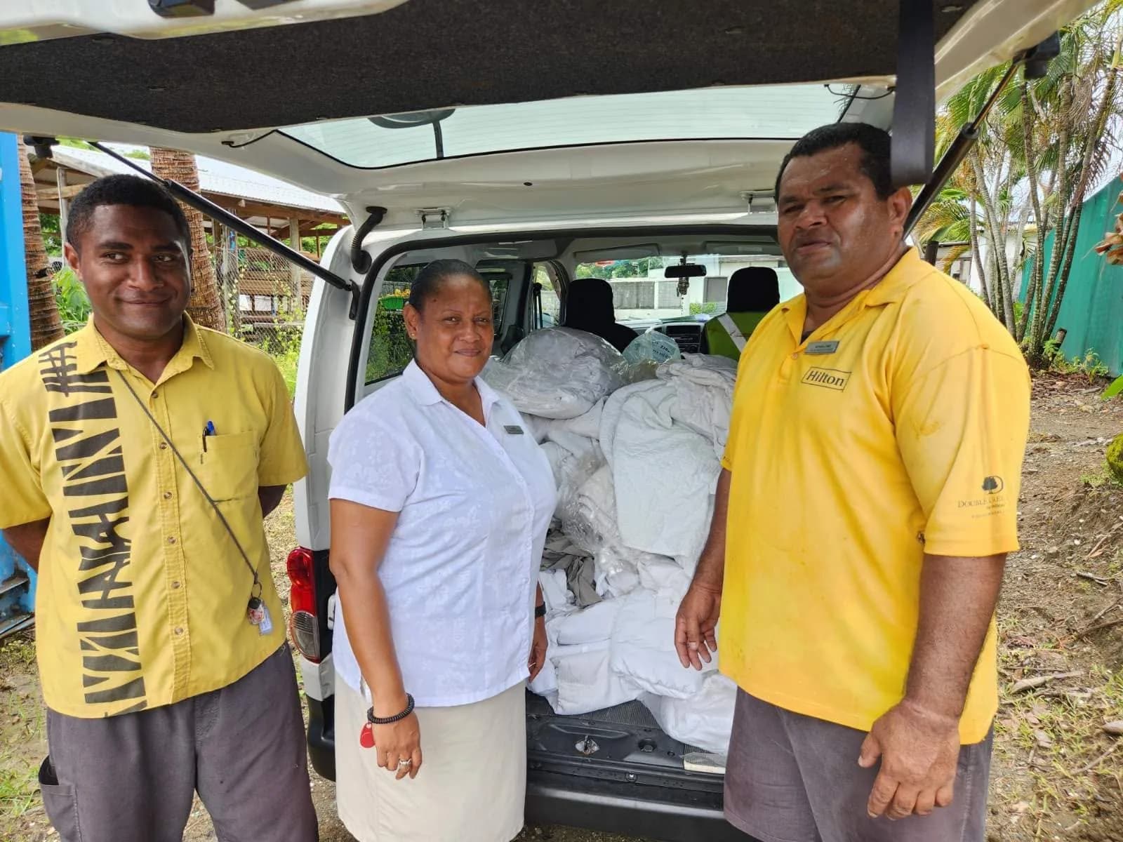 Hilton Fiji staff beside a vehicle loaded with donated linen