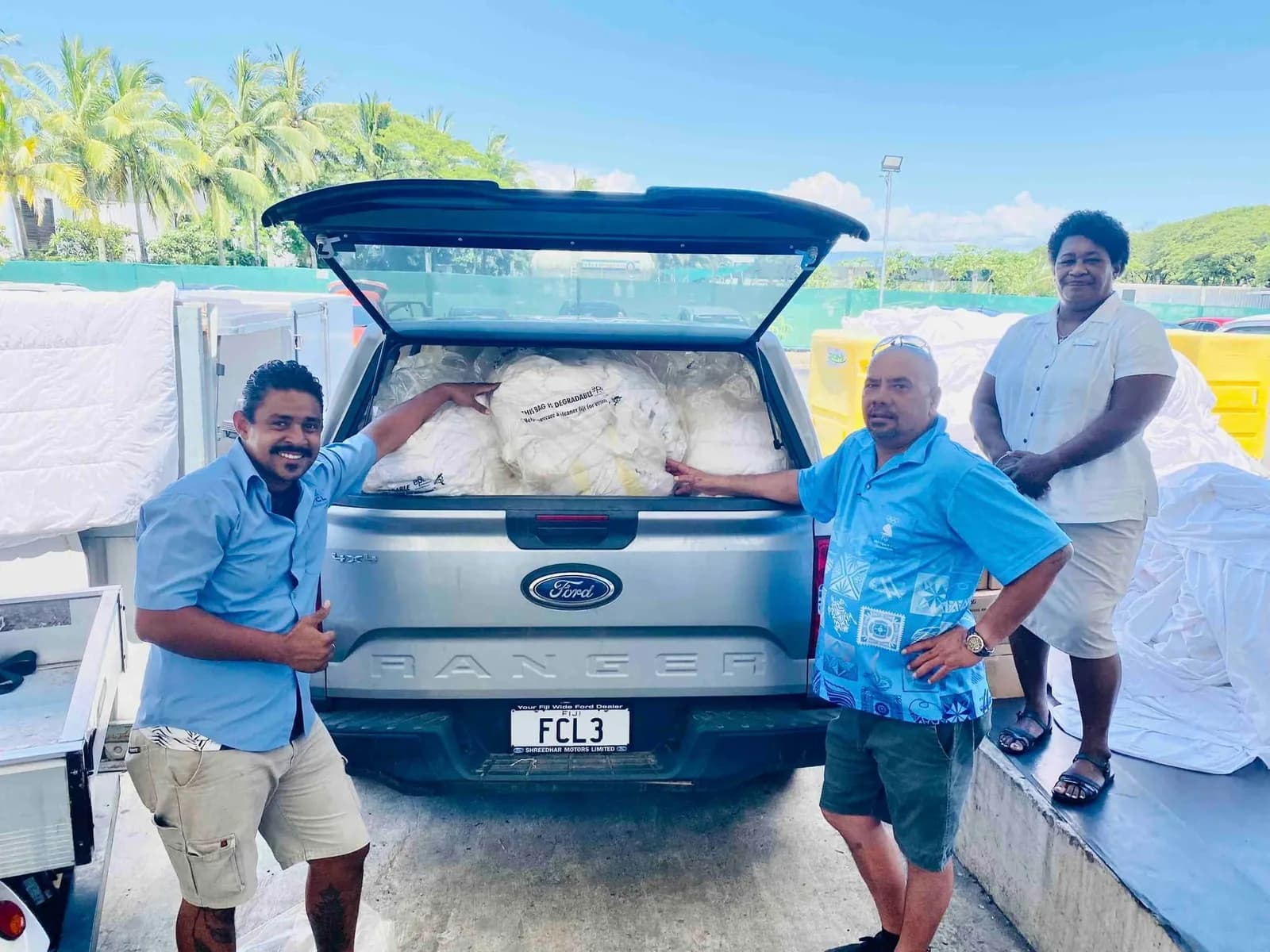 FCL and Hilton Fiji team members beside a vehicle filled with donated linen